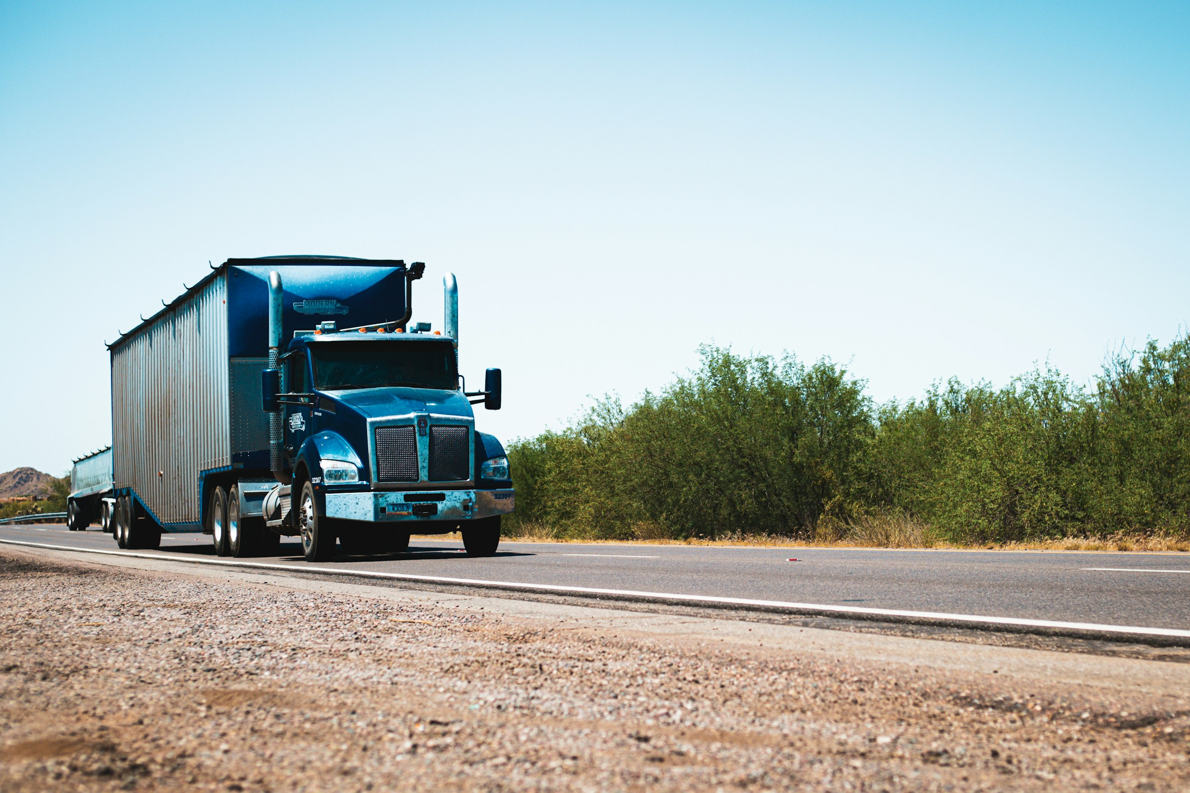Blue semi-truck on an open highway, representing the transportation businesses DEBO USA supports